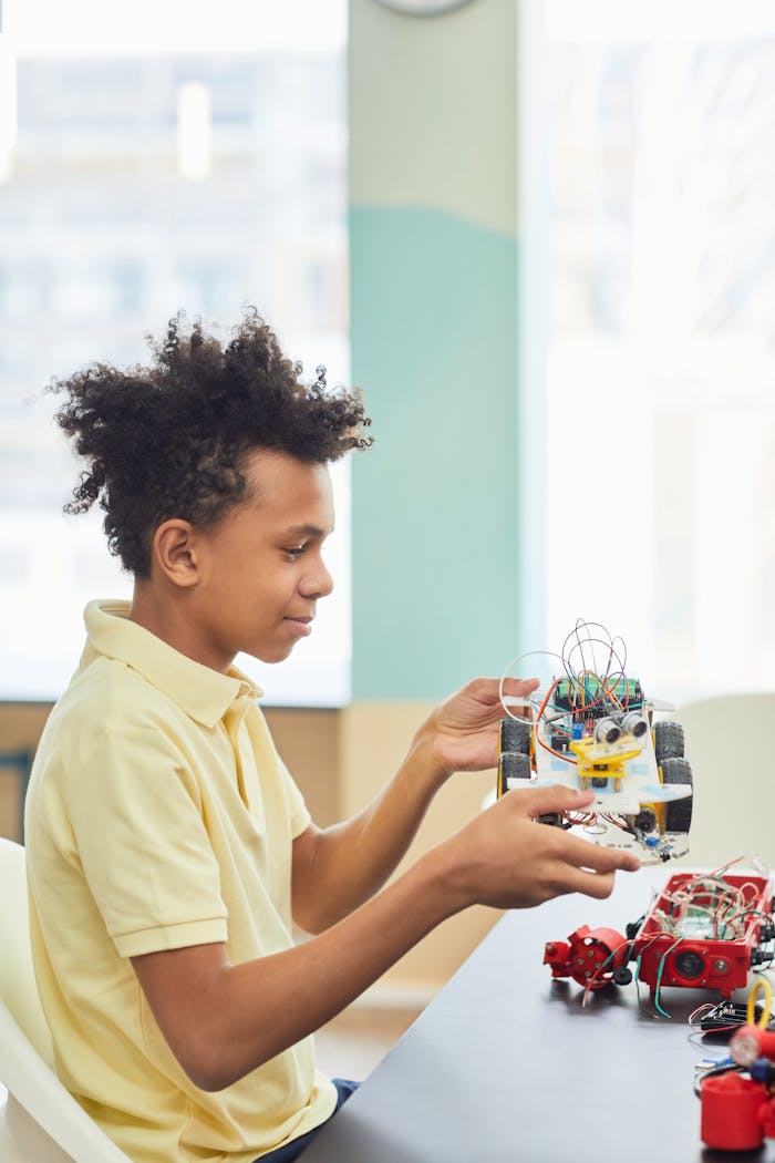 A young boy holds a robotic toy car indoors, focusing intently on learning and creativity.