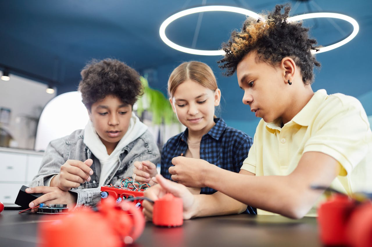 Diverse teenagers collaboratively working on a robotics project in a workshop.